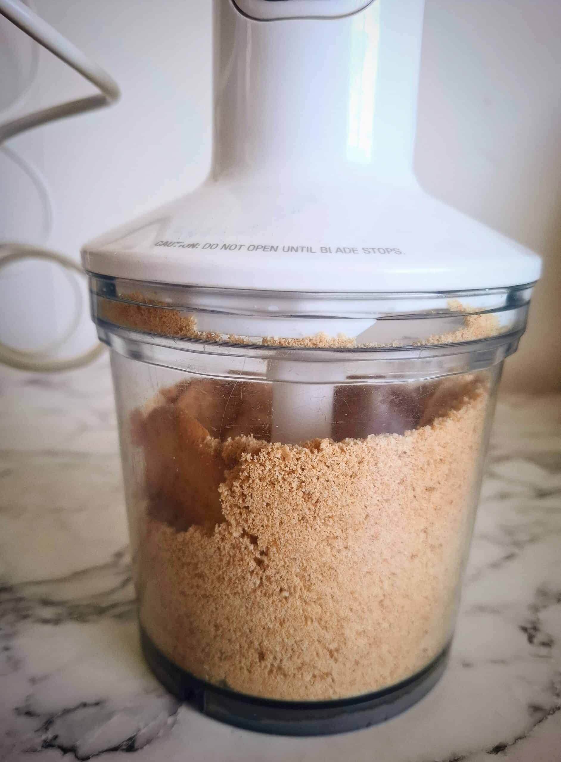 Digestive biscuits being blended to fine crumbs in a food processor.